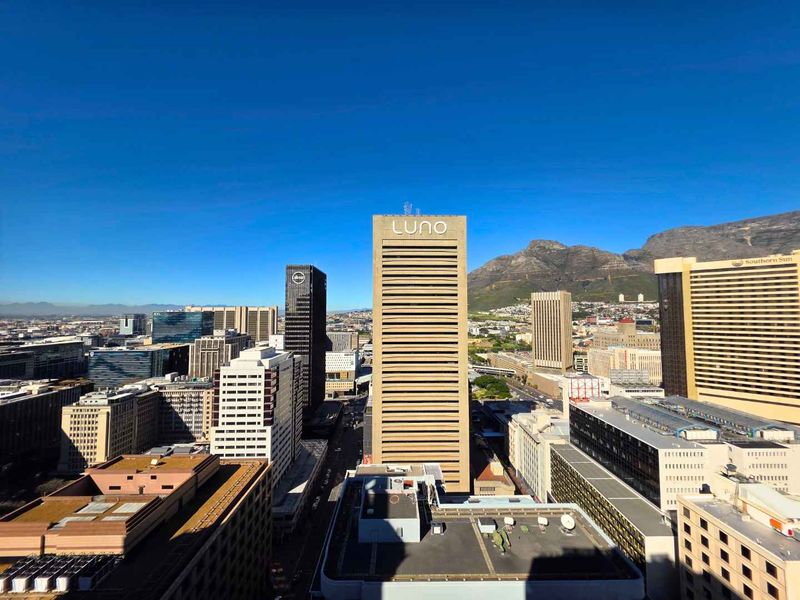An elevated city skyline view featuring prominent commercial high-rise buildings and a backdrop of Table Mountain.