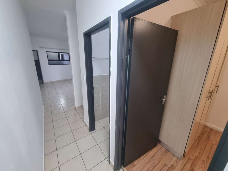 A clean, functional hallway featuring a mix of tiled and laminate flooring, providing access to multiple rooms with built-in storage.