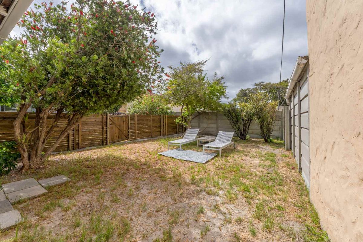 A private rear garden area featuring a mix of lawn, mature trees, and perimeter fencing, providing a quiet outdoor space.