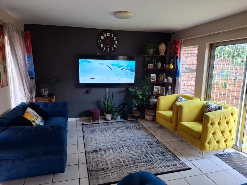 A comfortable living room featuring tiled flooring and a large sliding glass door that provides natural light and access to the outdoor area.