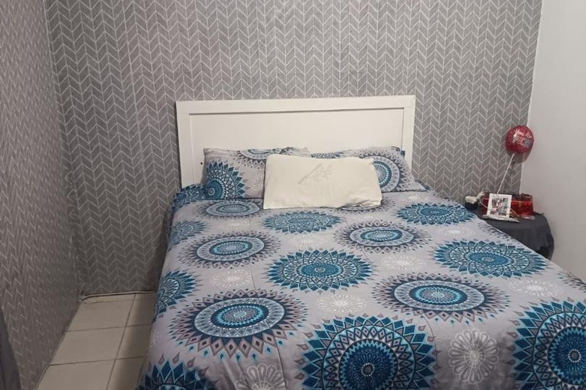 A bedroom featuring patterned wallpaper and tiled flooring.
