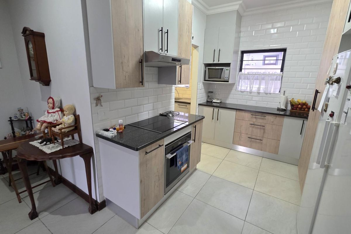 Modern kitchen featuring light wood and white cabinetry, granite countertops, subway tile backsplash, and integrated appliances including an oven and hob.