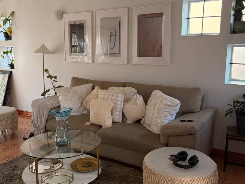 A cozy living room featuring terracotta floor tiles and grid-pattern windows, providing a warm and inviting atmosphere.