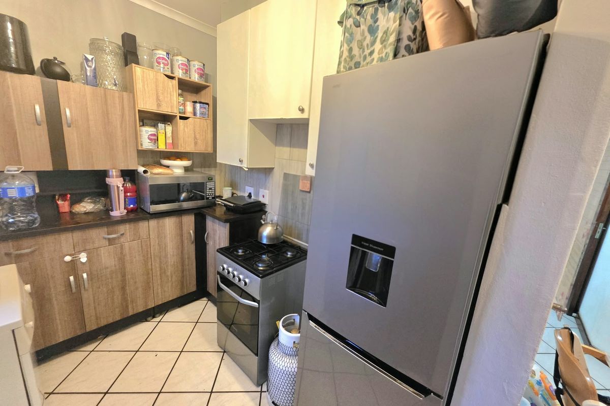 A compact kitchen featuring laminate cabinetry, tiled flooring, a gas stove, and a tiled backsplash, offering functional storage and preparation space.