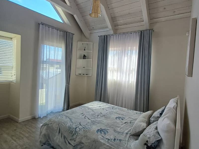 Bright bedroom featuring a high vaulted timber-clad ceiling, exposed rafters, and large windows that provide ample natural light.
