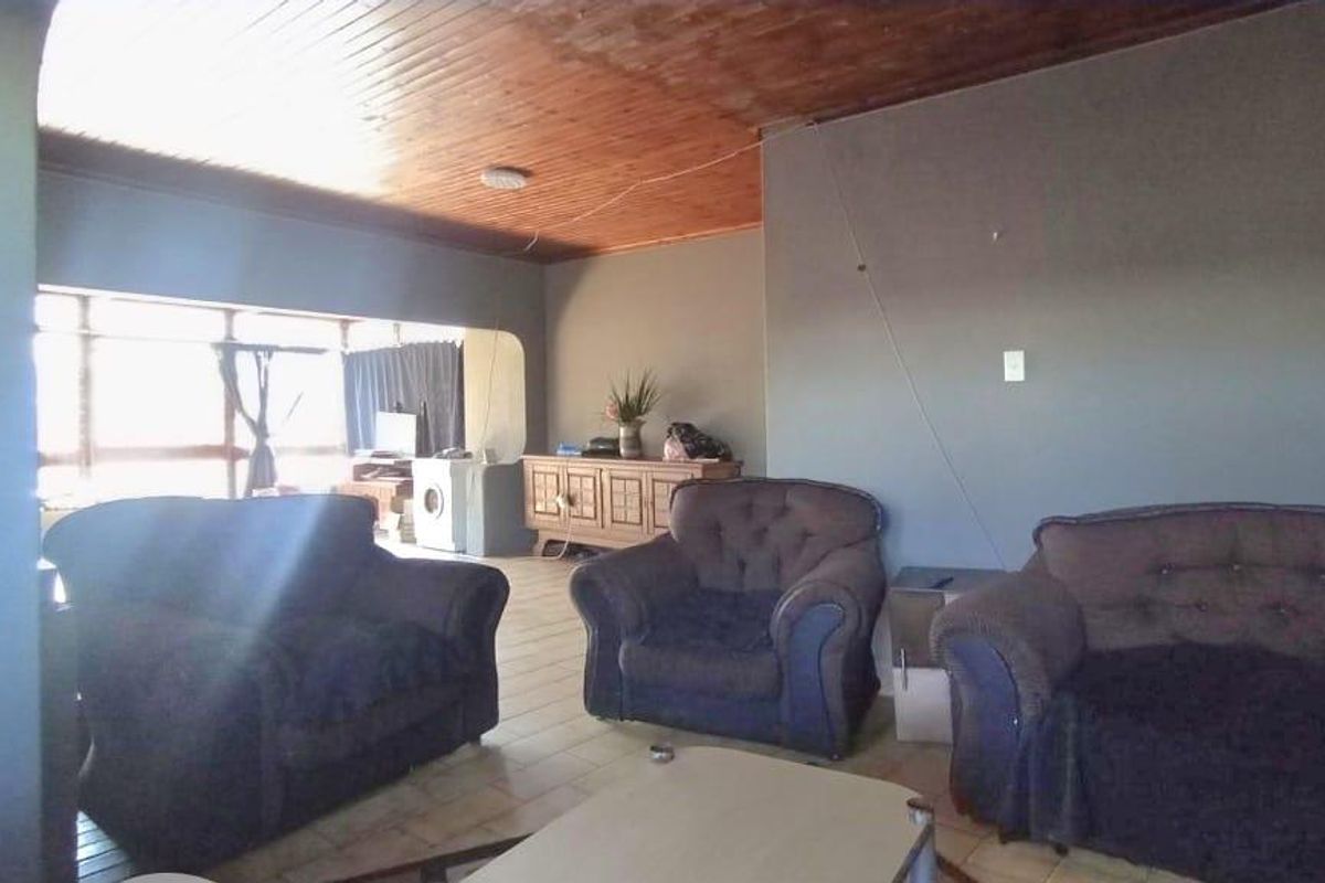 Spacious living area featuring a timber-paneled ceiling and large windows, offering a versatile layout for comfortable family living.