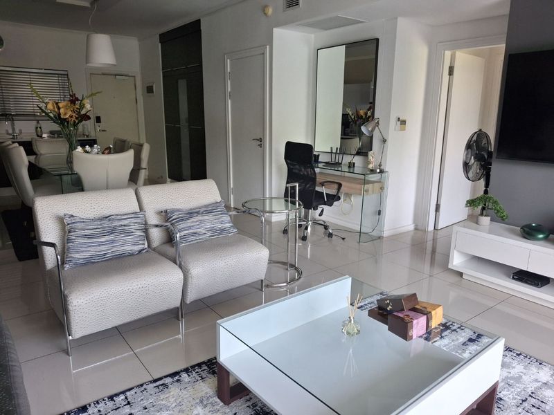 A bright open-plan living and dining area featuring polished tiled flooring, neutral walls, and integrated storage solutions, creating a modern and cohesive living space.