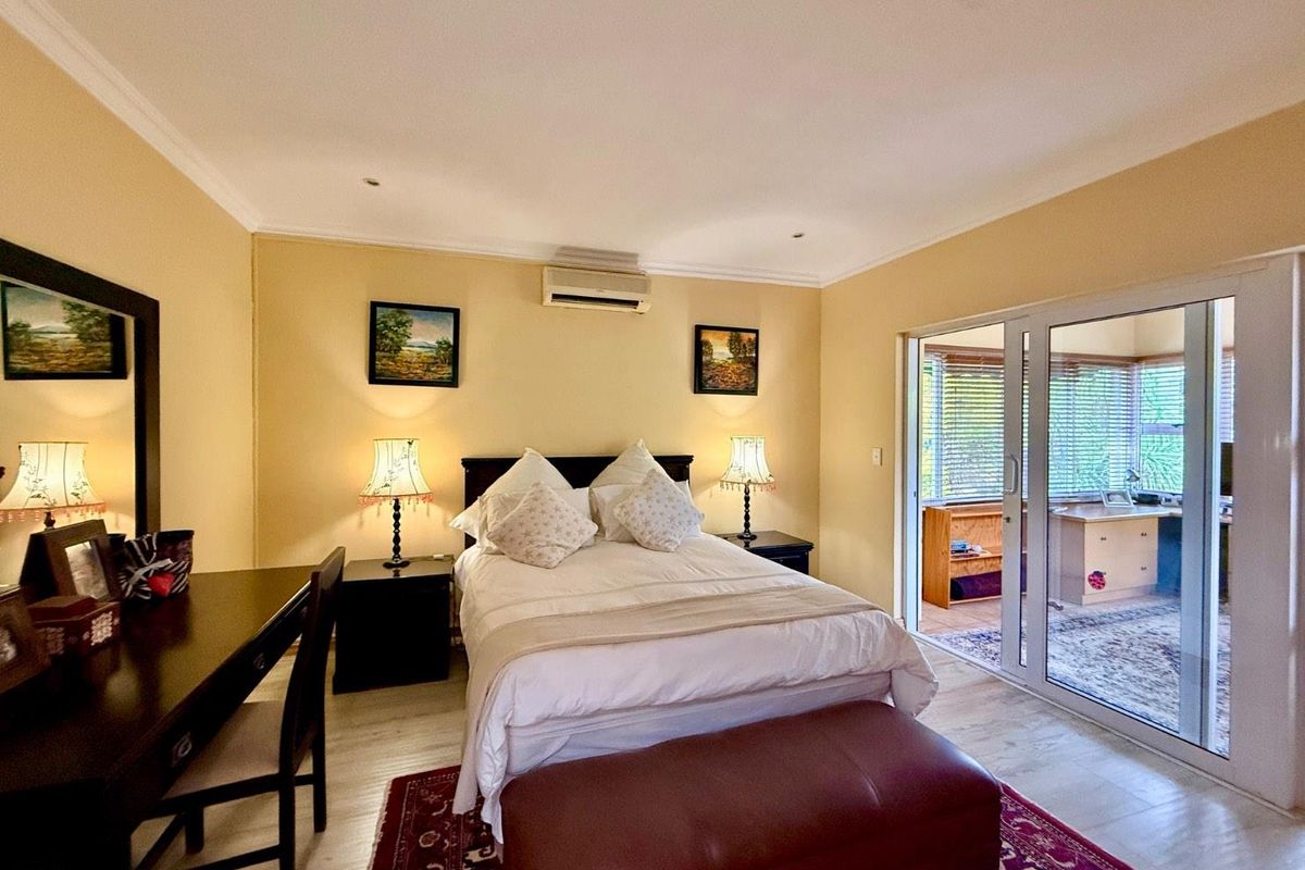 A well-maintained bedroom featuring recessed lighting, an integrated air conditioning unit, and sliding glass doors providing access to an adjacent room.