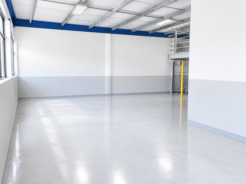 A clean, modern industrial utility space featuring polished epoxy flooring, exposed steel roof structure, and a functional mezzanine level with access ladder.