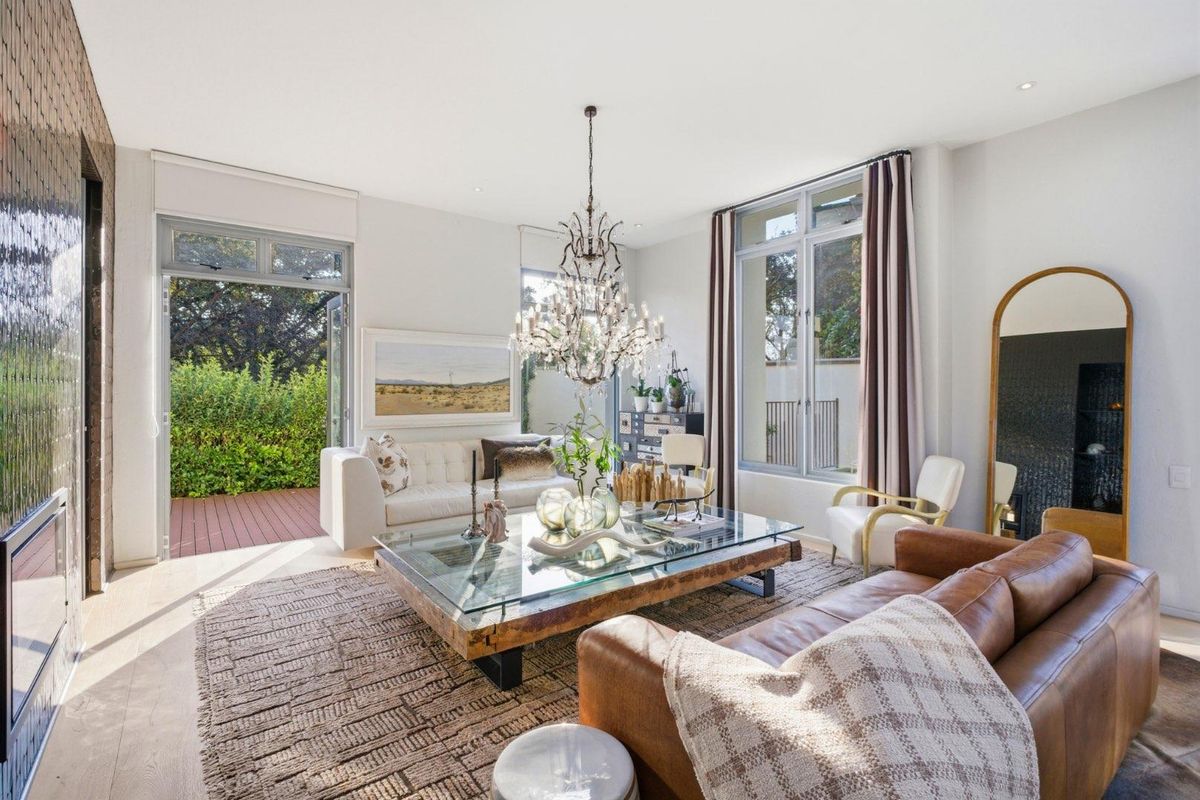 Bright and spacious living room featuring large windows, a built-in fireplace, and direct access to an outdoor deck area.