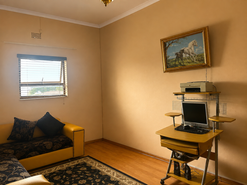 A bedroom featuring laminate flooring and a window with venetian blinds, offering a neutral canvas for potential interior updates.