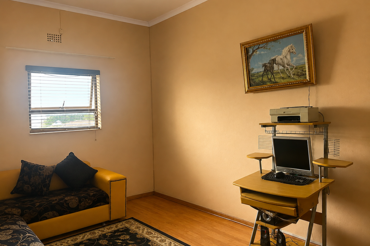 A bedroom featuring laminate flooring and a window with venetian blinds, offering a neutral canvas for potential interior updates.
