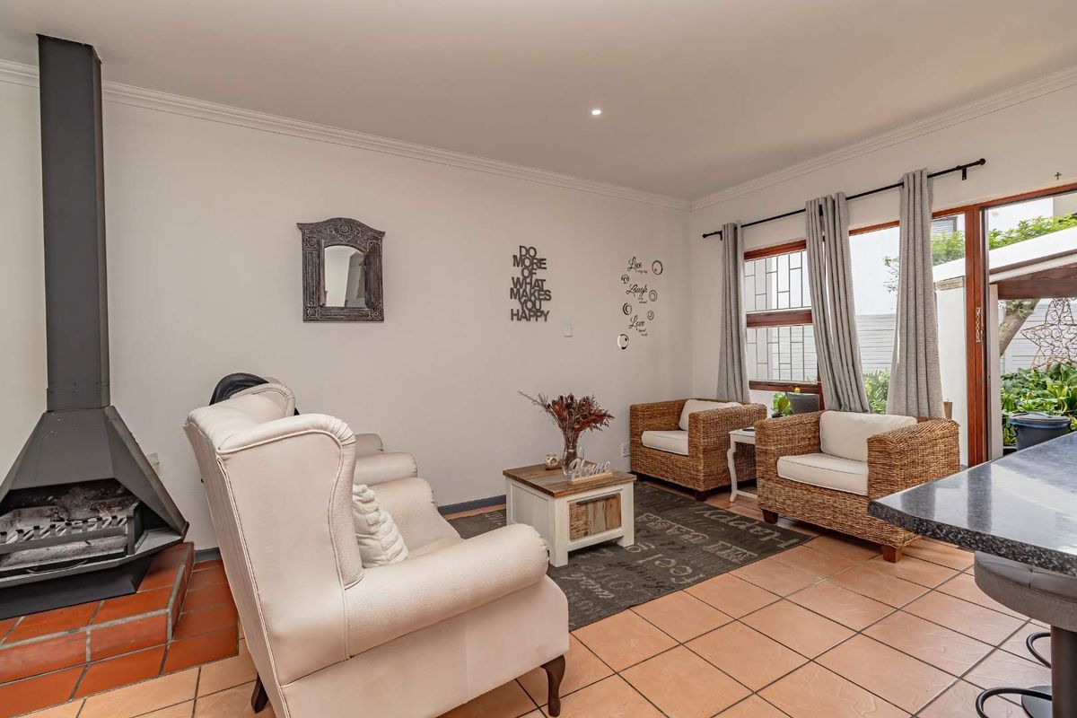 A cozy living area featuring a built-in fireplace, tiled flooring, and large windows providing natural light and access to the outdoor space.
