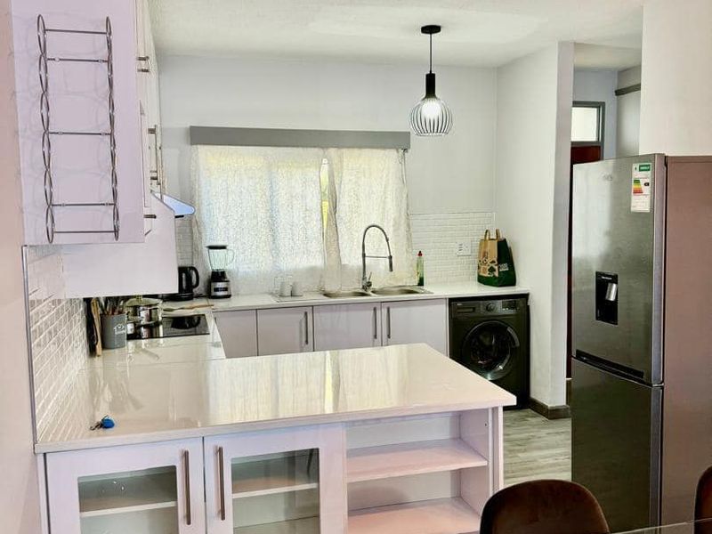Modern kitchen featuring white cabinetry, quartz countertops, subway tile backsplash, and integrated lighting, creating a clean and functional culinary space.