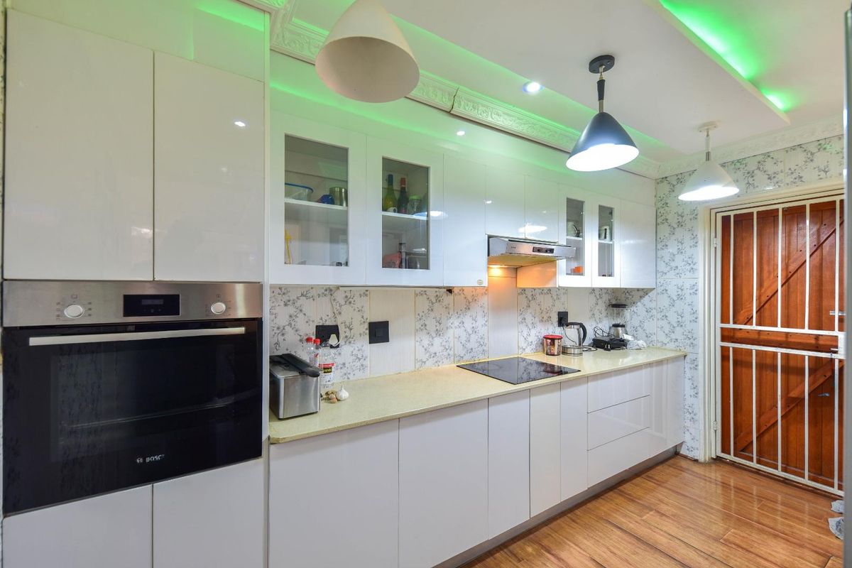 Modern kitchen featuring white gloss cabinetry, built-in oven, electric hob, extractor fan, and decorative ceiling cornice with integrated lighting.