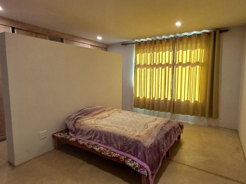 A spacious bedroom featuring a functional partition wall, built-in wardrobe storage, and recessed ceiling lighting, offering a clean and modern layout.