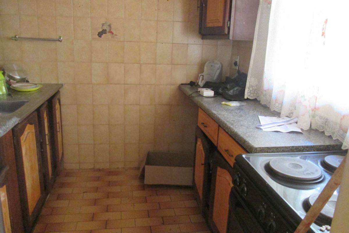 A dated kitchen featuring built-in cabinetry, tiled backsplash, stone-look countertops, and an electric stove, offering potential for a modern renovation.