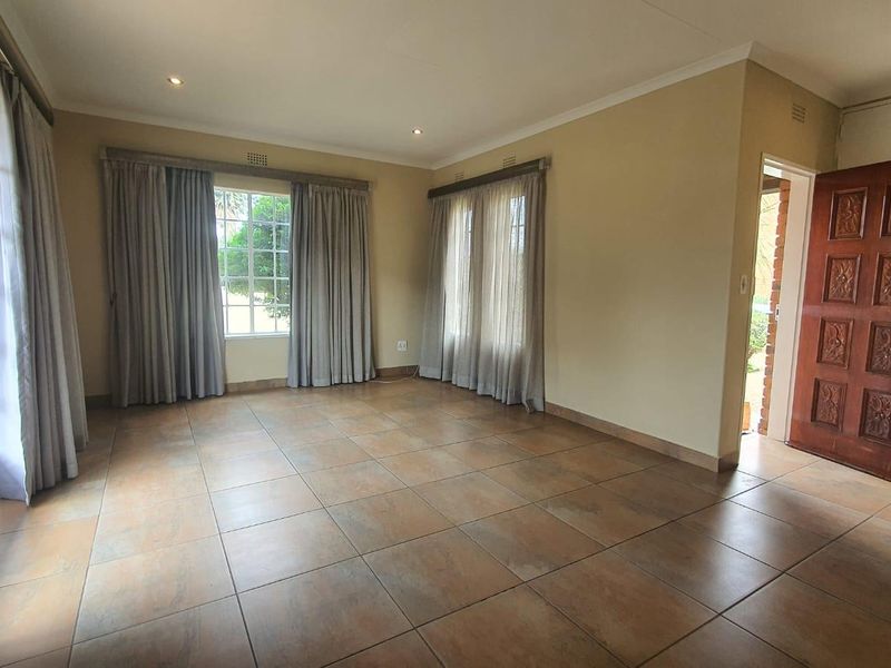Spacious living area featuring neutral tiled flooring, recessed lighting, and direct access to the exterior through french doors.