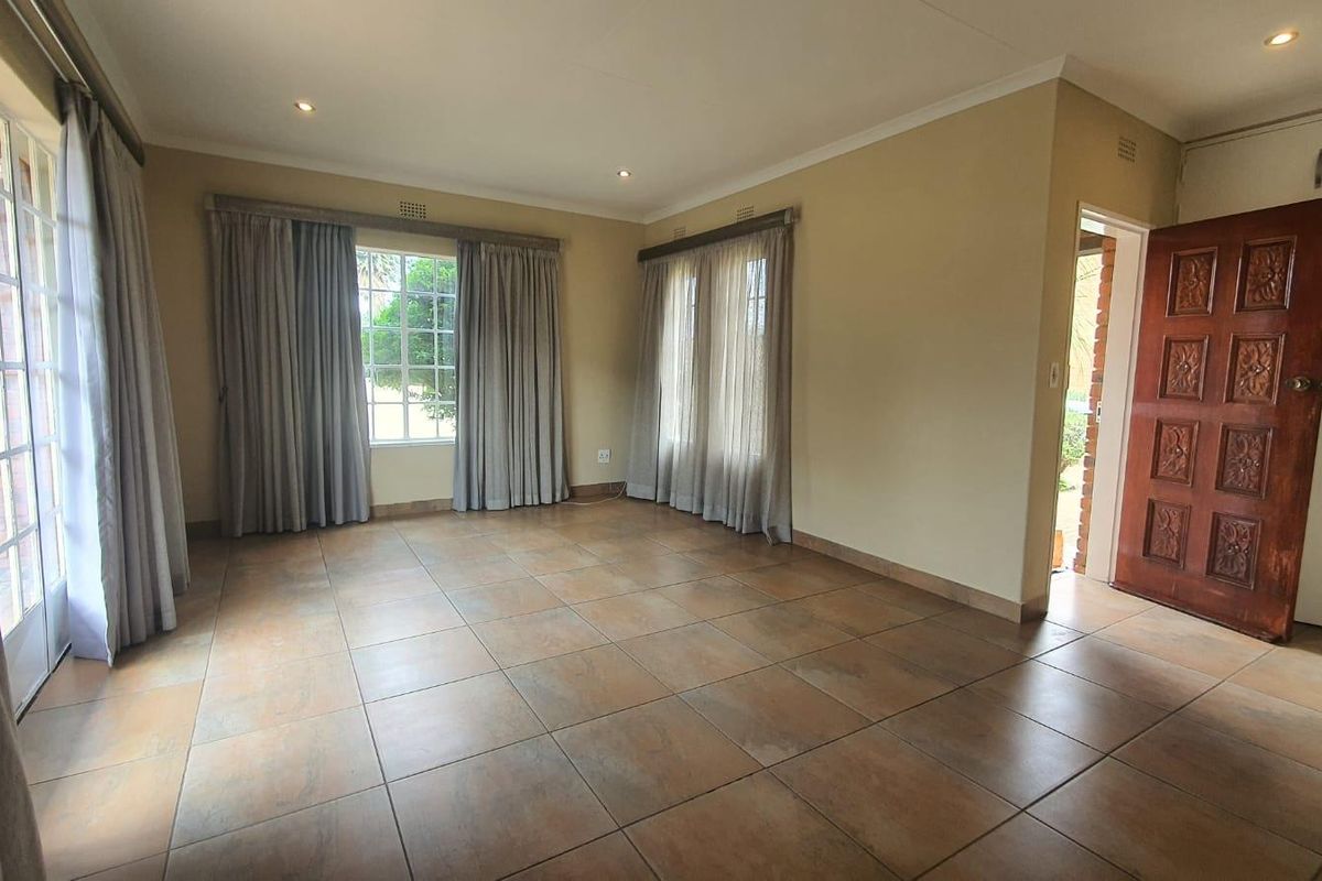 Spacious living area featuring neutral tiled flooring, recessed lighting, and direct access to the exterior through french doors.