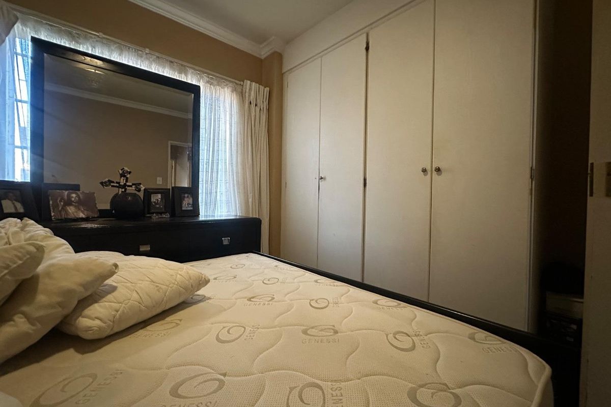 A bedroom featuring built-in floor-to-ceiling wardrobes and crown molding, providing ample storage space.