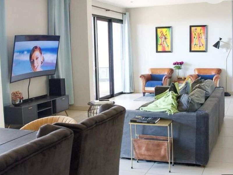 Spacious open-plan living area featuring tiled flooring, recessed lighting, and large sliding glass doors leading to an outdoor space.