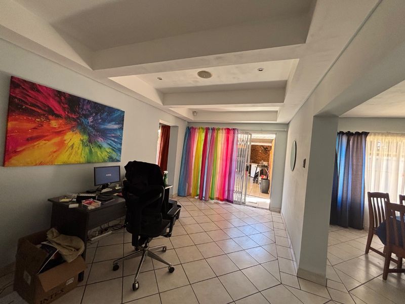 Open plan living area featuring tiled flooring, a recessed ceiling with downlights, and a sliding glass door leading to an outdoor space.