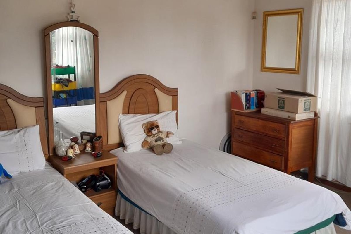 A bedroom featuring exposed timber ceiling beams, carpeted flooring, and a window with curtain treatments.