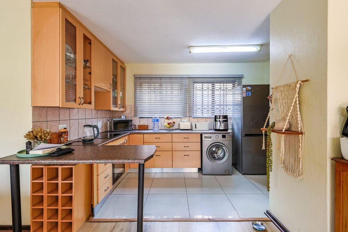 Functional kitchen featuring light wood cabinetry, tiled flooring, integrated oven, and a dedicated space for a washing machine.