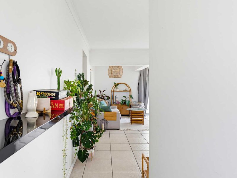 A bright living area featuring neutral tiled flooring and a built-in wall shelf, creating a welcoming and open transition space within the apartment.
