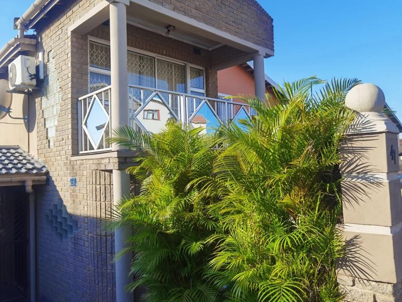 An elevated balcony featuring a decorative metal balustrade, brick exterior walls, and an integrated air conditioning unit.