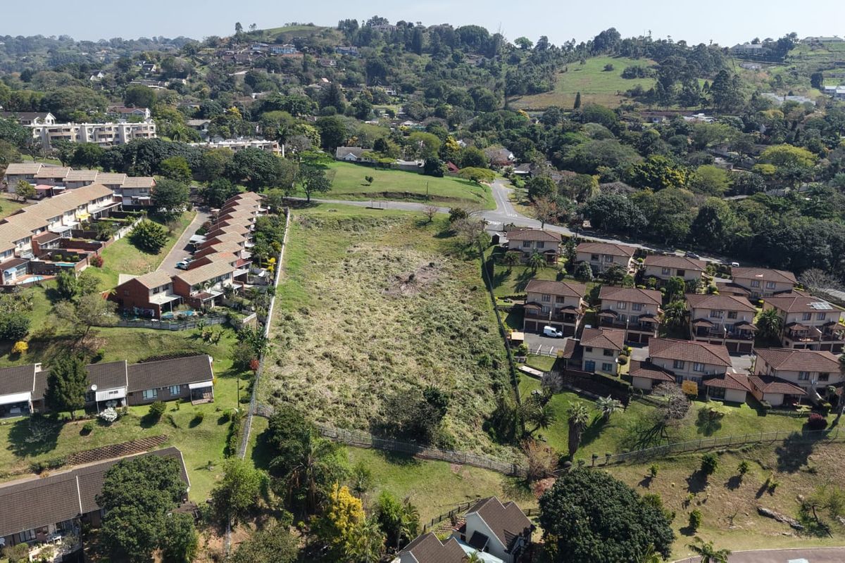 An aerial view of a vacant residential plot situated within an established suburban neighborhood, surrounded by existing residential developments.