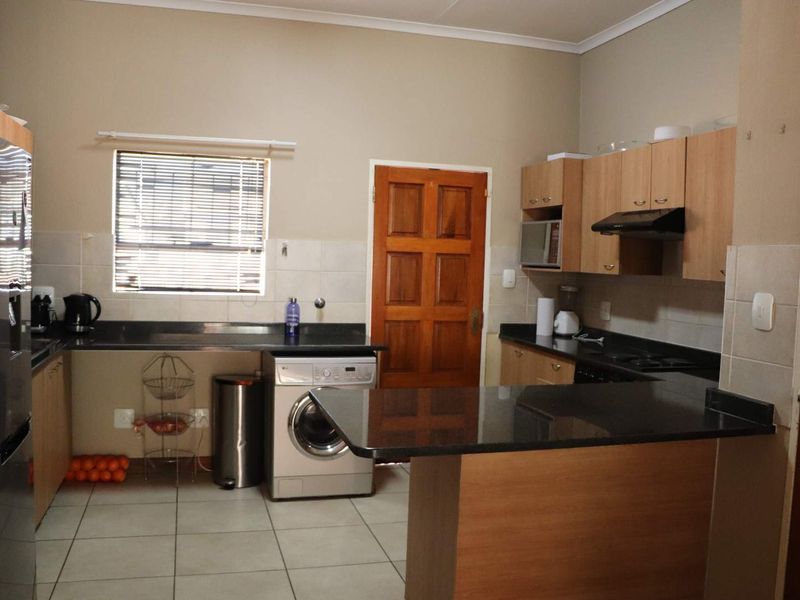 Functional kitchen featuring laminate cabinetry, granite countertops, tiled flooring, and a built-in oven with an extractor fan.