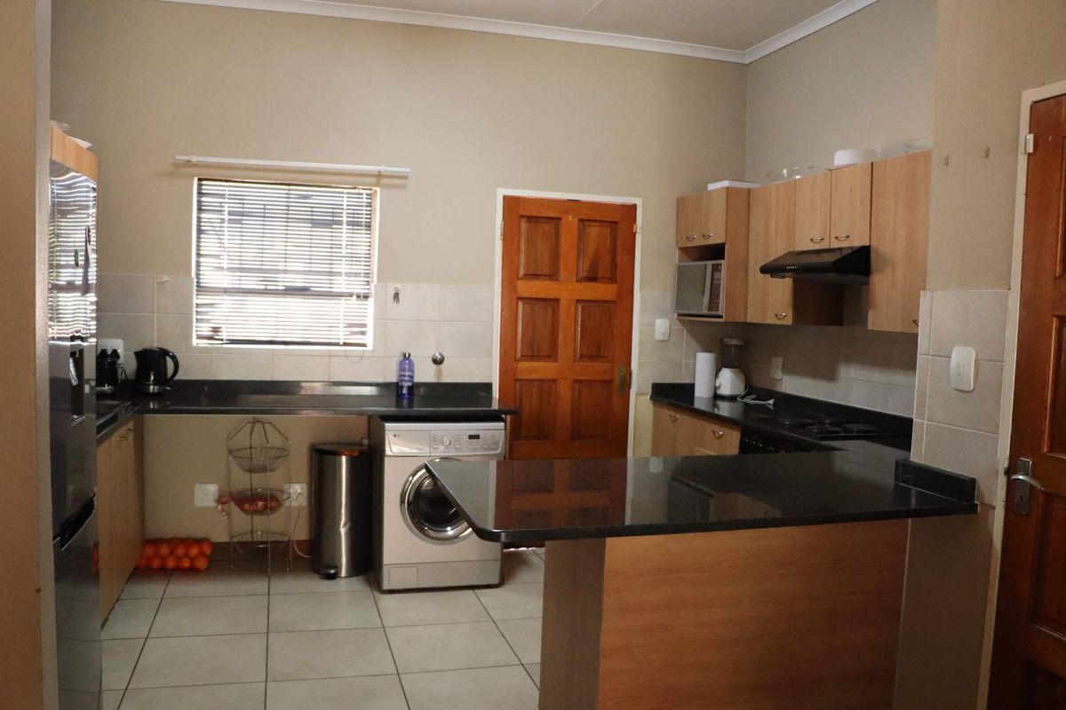 Functional kitchen featuring laminate cabinetry, granite countertops, tiled flooring, and a built-in oven with an extractor fan.