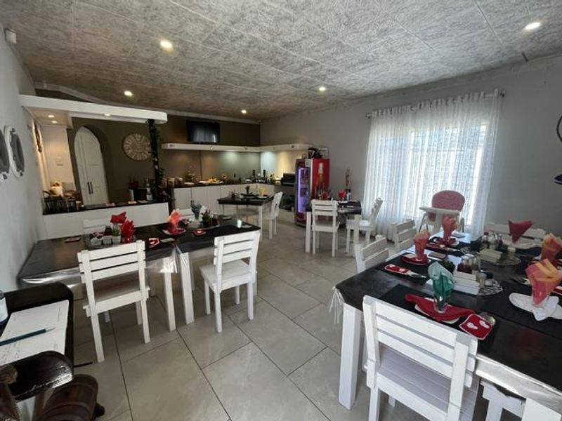 Spacious open-plan dining and service area featuring tiled flooring, recessed lighting, and a built-in serving counter with an adjacent archway.