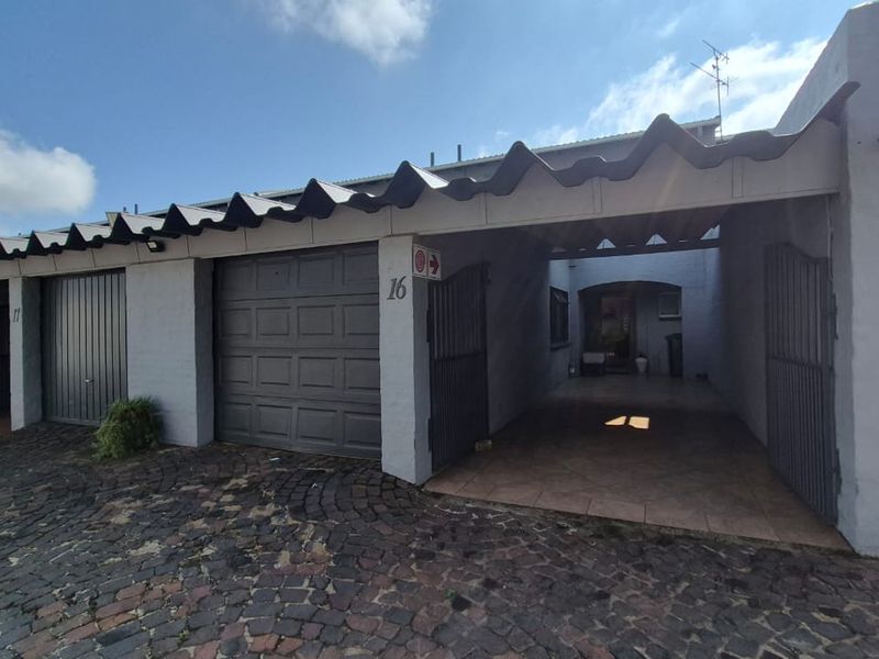Front exterior view of the townhouse featuring a single garage, covered carport, and cobblestone driveway access.