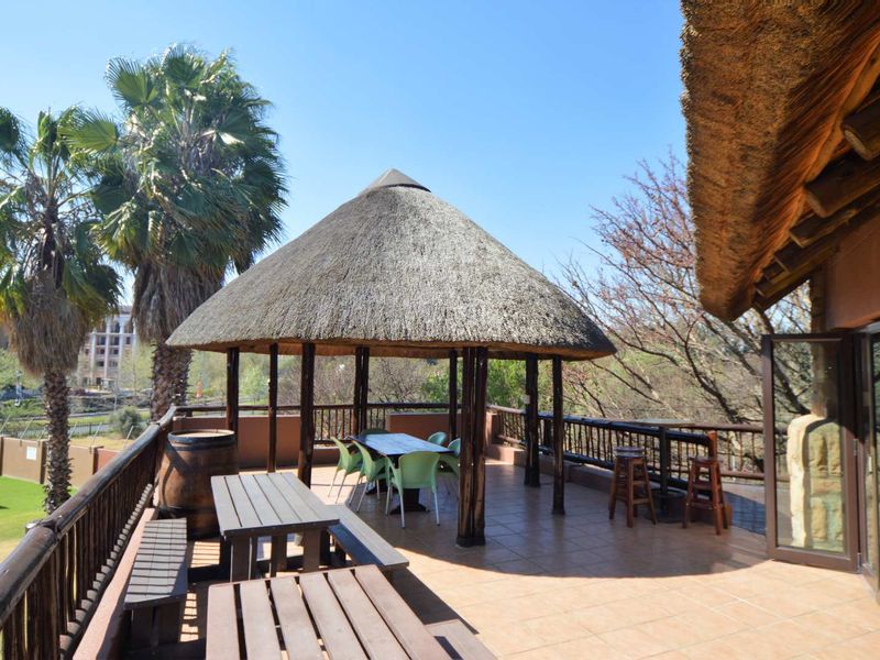 Spacious outdoor balcony featuring a thatched roof gazebo, tiled flooring, and timber balustrades, offering an ideal area for outdoor relaxation and entertainment.