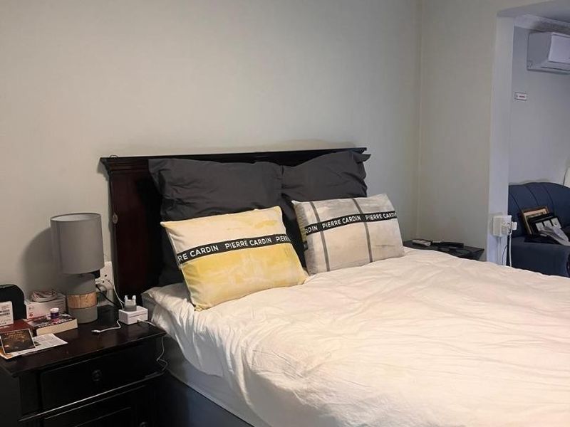 A bedroom featuring tiled flooring, crown molding, and a wall-mounted split-system air conditioning unit.