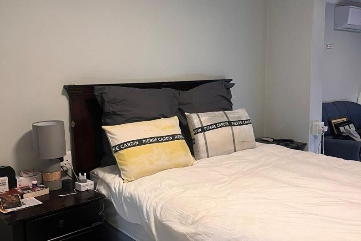 A bedroom featuring tiled flooring, crown molding, and a wall-mounted split-system air conditioning unit.