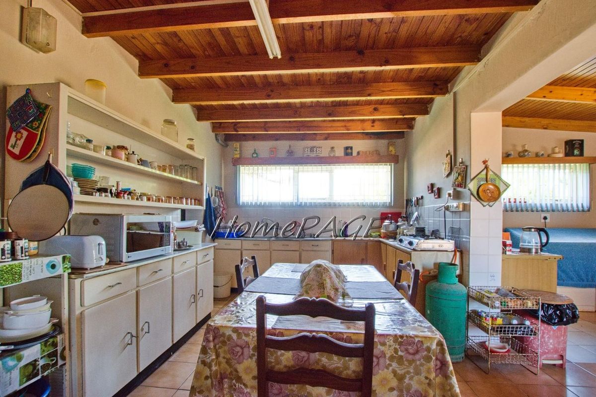 A rustic kitchen featuring exposed timber ceiling beams, built-in cabinetry, and tiled flooring, offering a functional layout with potential for modernization.