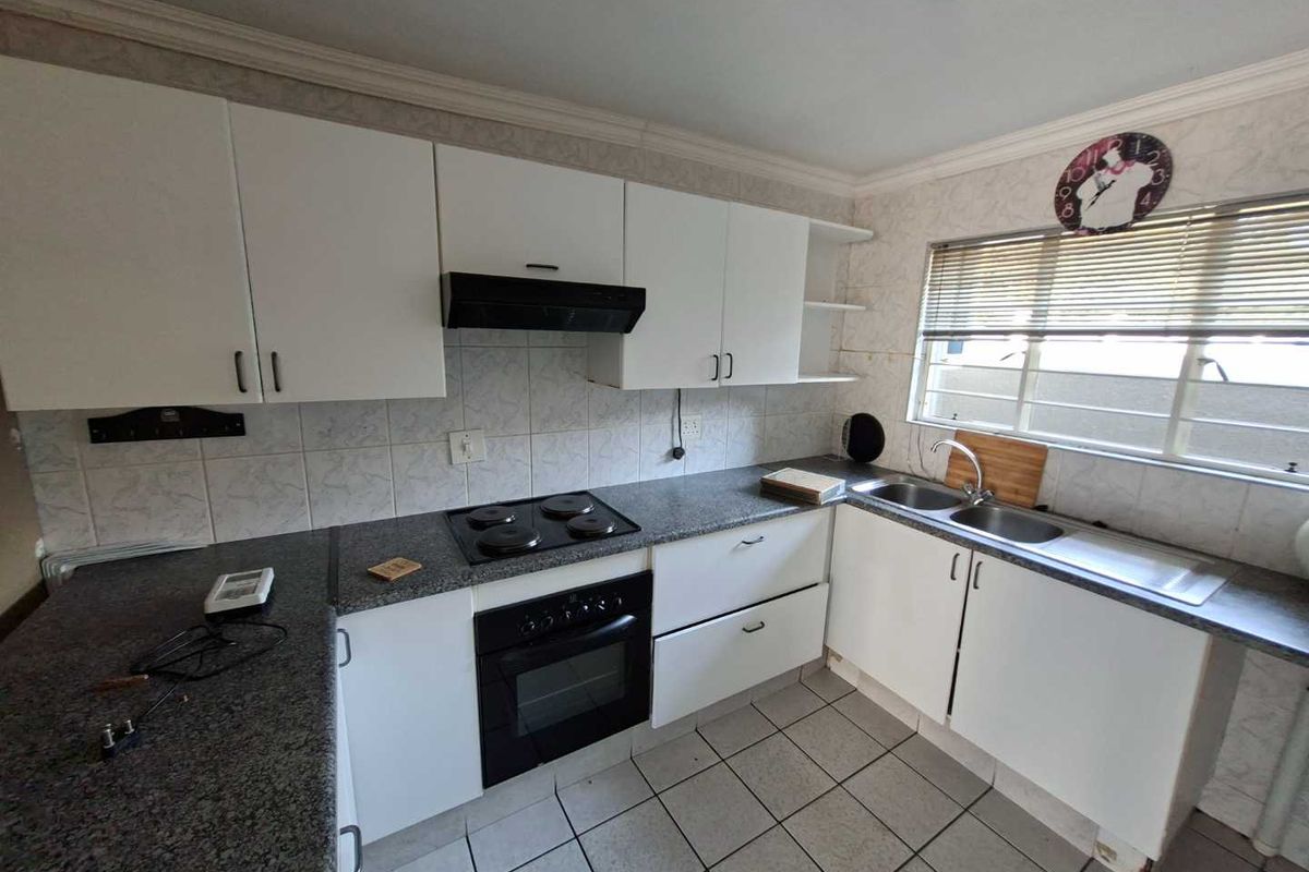 Functional kitchen featuring white cabinetry, granite countertops, built-in oven, electric hob, extractor fan, and a double basin sink with tiled finishes.