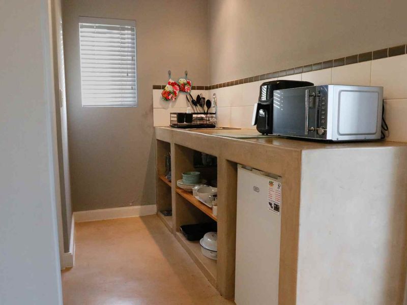 A functional scullery area featuring a built-in concrete countertop, integrated sink, and tiled backsplash, providing practical utility space.