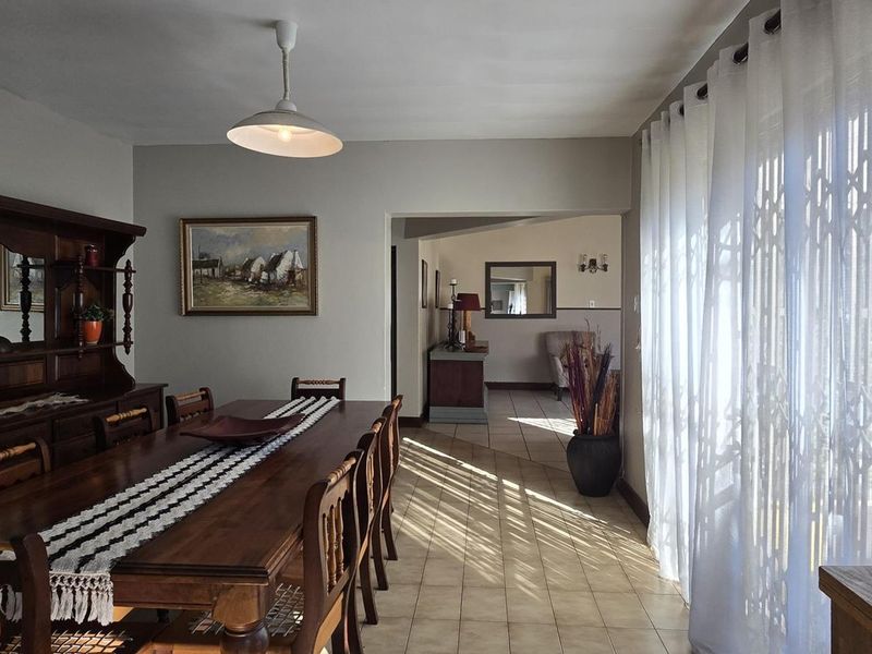 A dining room featuring tiled flooring, pendant lighting, and large sliding glass doors with security gates leading to an outdoor area.