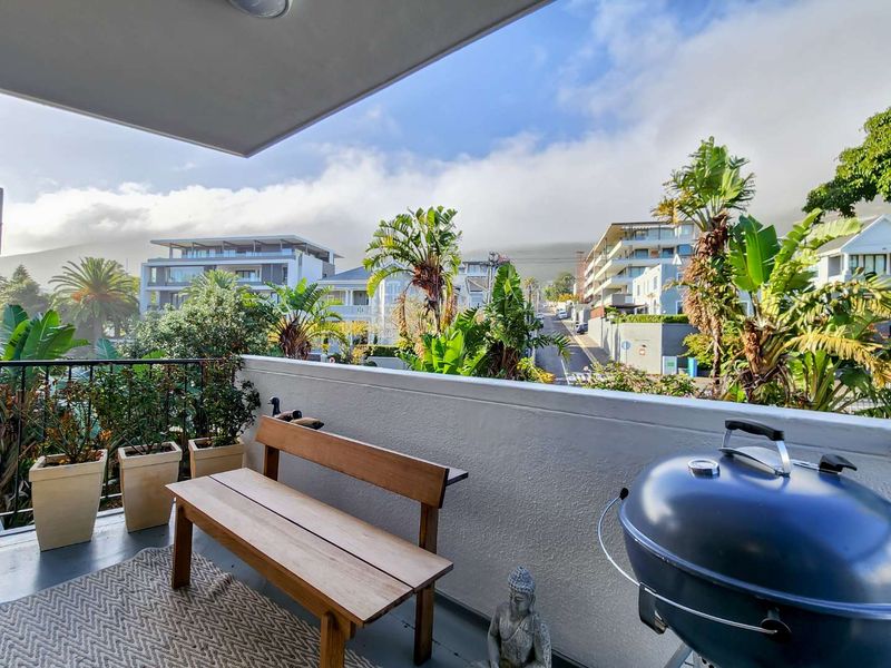 A covered balcony featuring a metal railing and concrete balustrade, offering an elevated view of the surrounding street and neighbourhood.