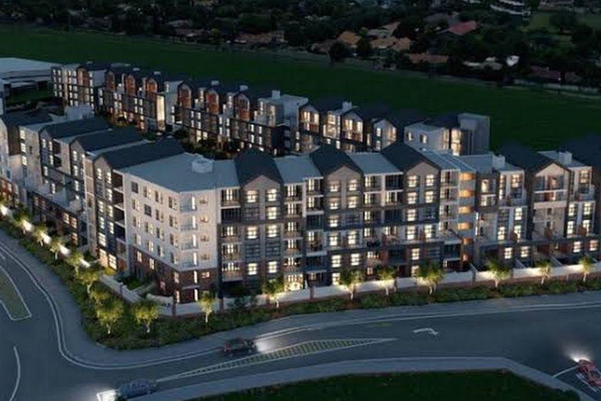 An aerial view of a modern multi-story apartment complex development, showcasing the building architecture, exterior facade, and surrounding street layout.