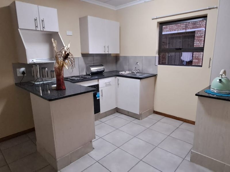 A functional kitchen featuring granite countertops, built-in cabinetry, and tiled flooring, offering a practical layout for daily meal preparation.