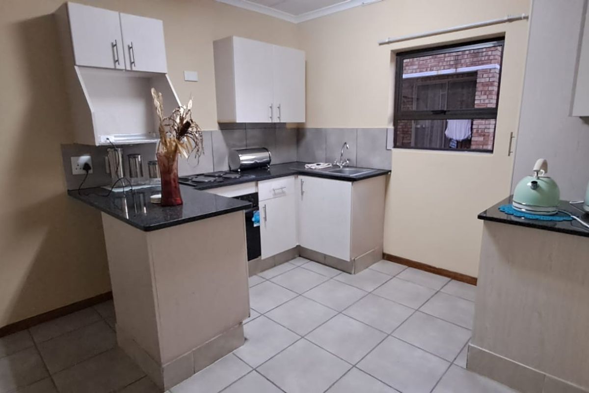 A functional kitchen featuring granite countertops, built-in cabinetry, and tiled flooring, offering a practical layout for daily meal preparation.