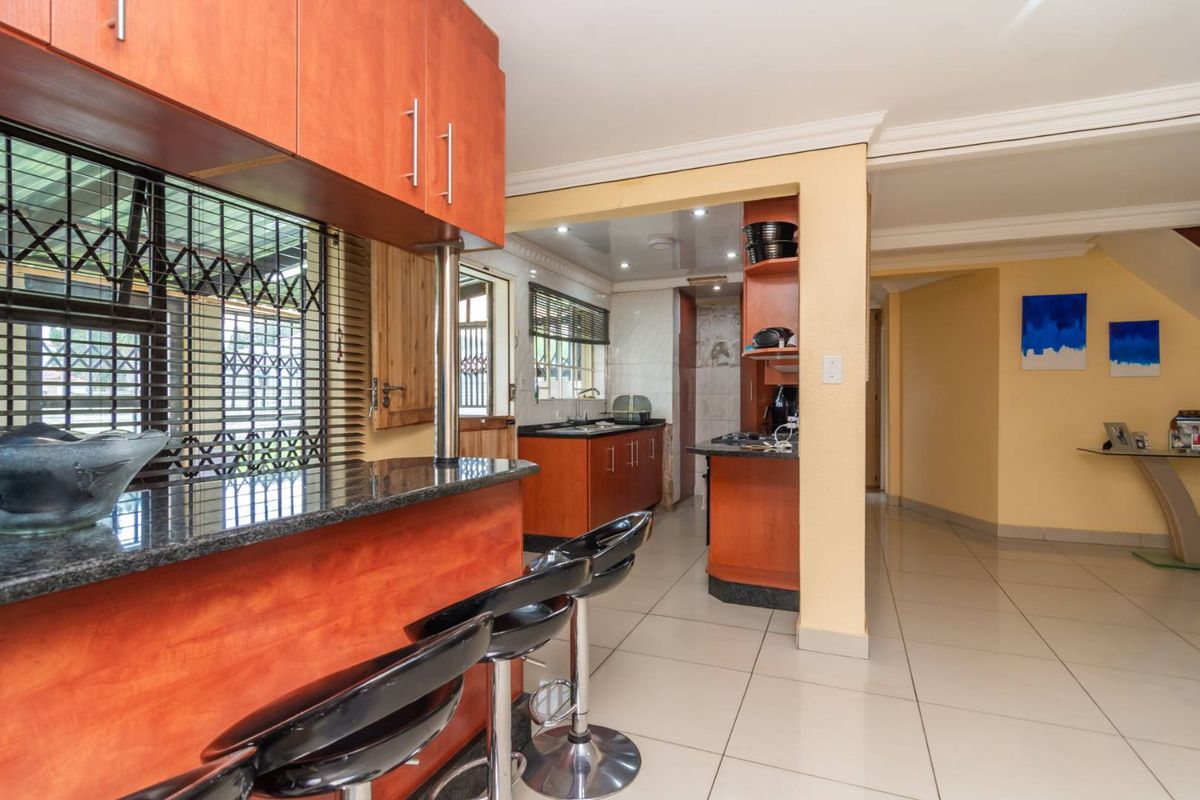 A functional kitchen featuring wooden cabinetry, granite countertops, a breakfast bar, and tiled flooring, providing a practical layout for daily meal preparation.