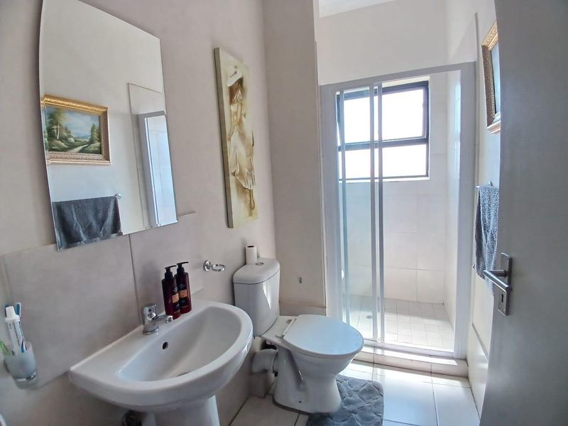 A functional bathroom featuring a pedestal basin, toilet, and a separate shower enclosure with tiled finishes.