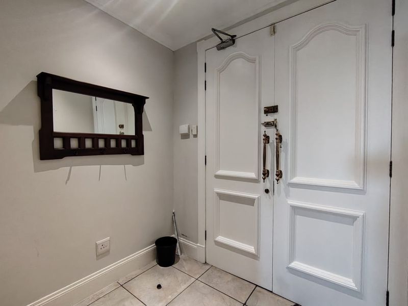 A functional entry area featuring double doors, tiled flooring, and neutral wall finishes.