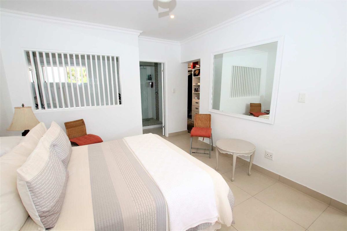A bright bedroom featuring tiled flooring, a built-in closet, and an en-suite bathroom with a shower.